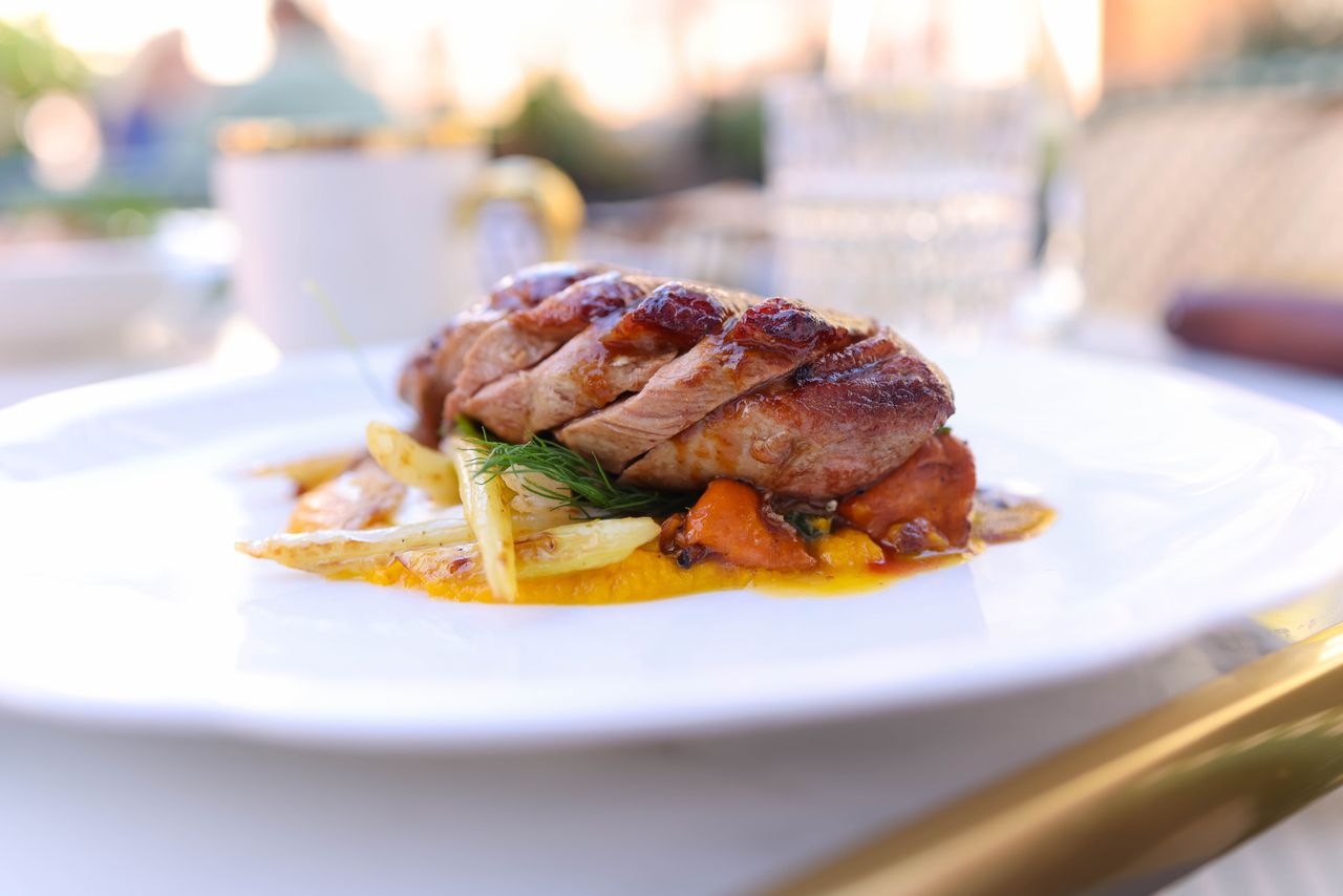 A succulent beef dish garnished with roasted vegetables served on a white plate.