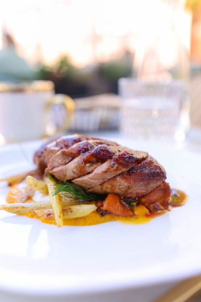 A beautifully plated gourmet roast duck dish with vibrant vegetables, perfect for fine dining settings.