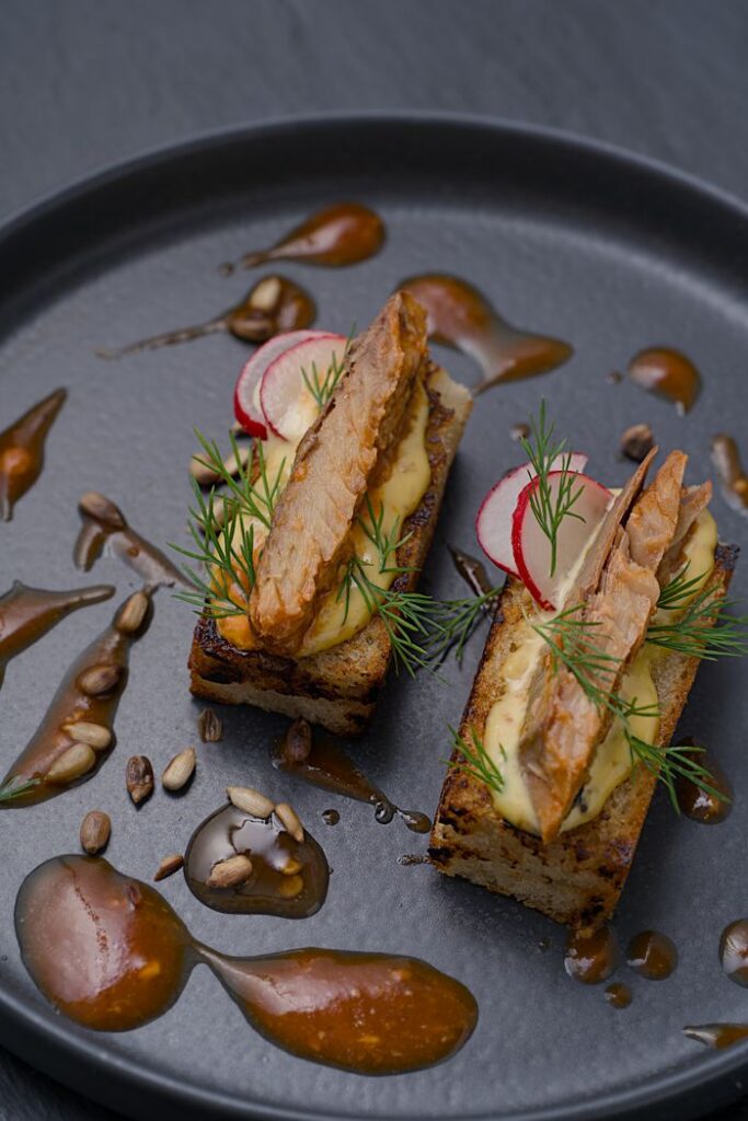 Elegant presentation of smoked fish on bread with creamy sauce and garnish.